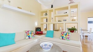 Un salon comprenant un ensemble de canapés, une table basse et une étagère sur laquelle sont disposés divers objets décoratifs.