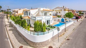 Ein modernes Haus mit Pool, einer geschwungenen Auffahrt und Blick auf die Straße.