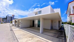 A modern building with a flat roof, large windows, and a covered entrance area. - Kariyushi Condominium Resort Onna Maeda Base (Onna)