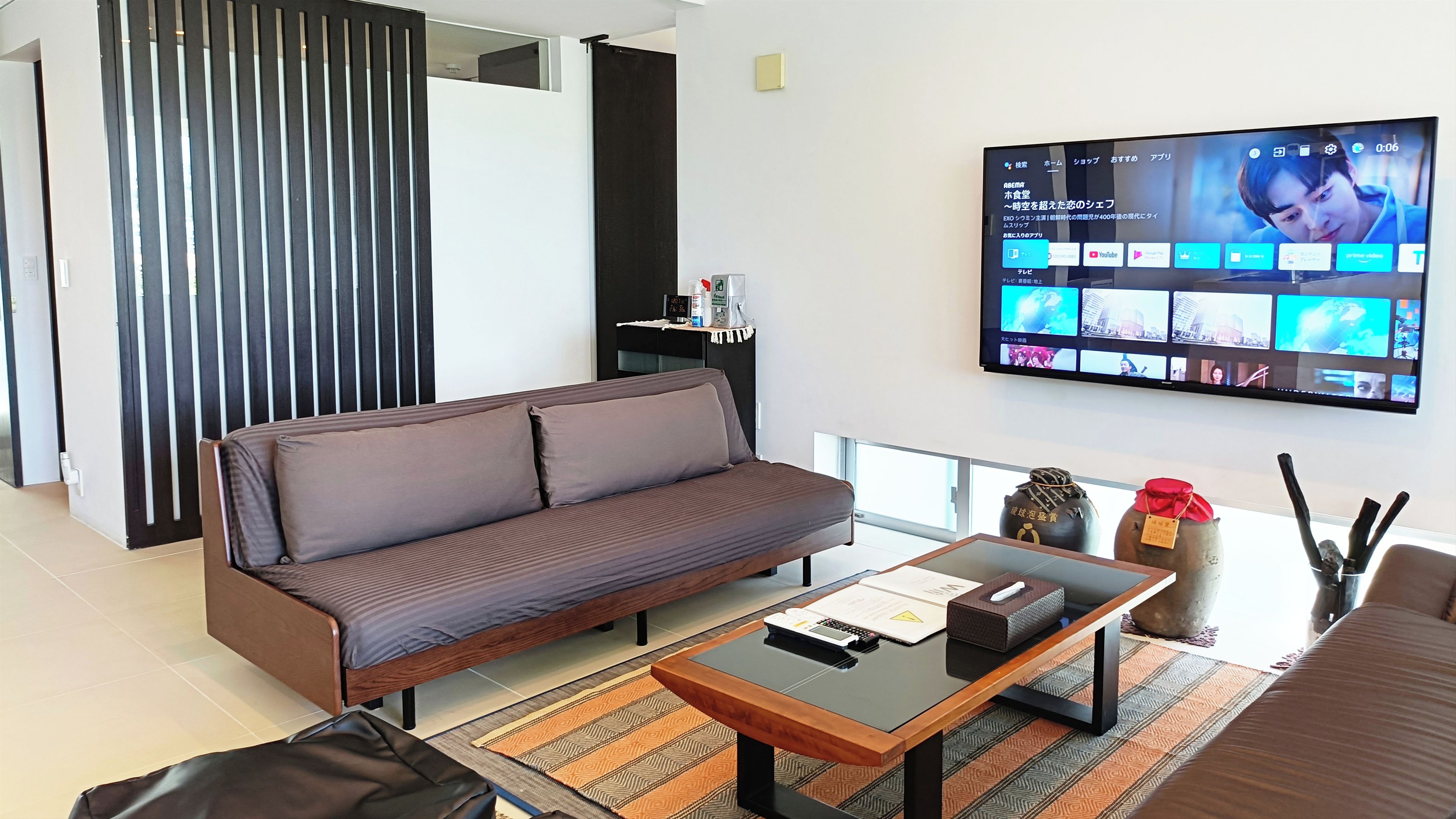 A modern living room with a sofa, coffee table, and a flat-screen TV displaying a video call interface.