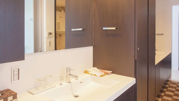 Ein modernes Badezimmer mit einem weißen Waschbecken, einem Spiegel und einer dunklen Holztür.