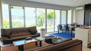 Ein modernes Wohnzimmer mit einem braunen Ledersofa, einem Glastisch und einem Essbereich mit einem Holztisch und Stühlen.