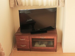 A flat-screen TV on a wooden cabinet with a glass-fronted storage compartment.