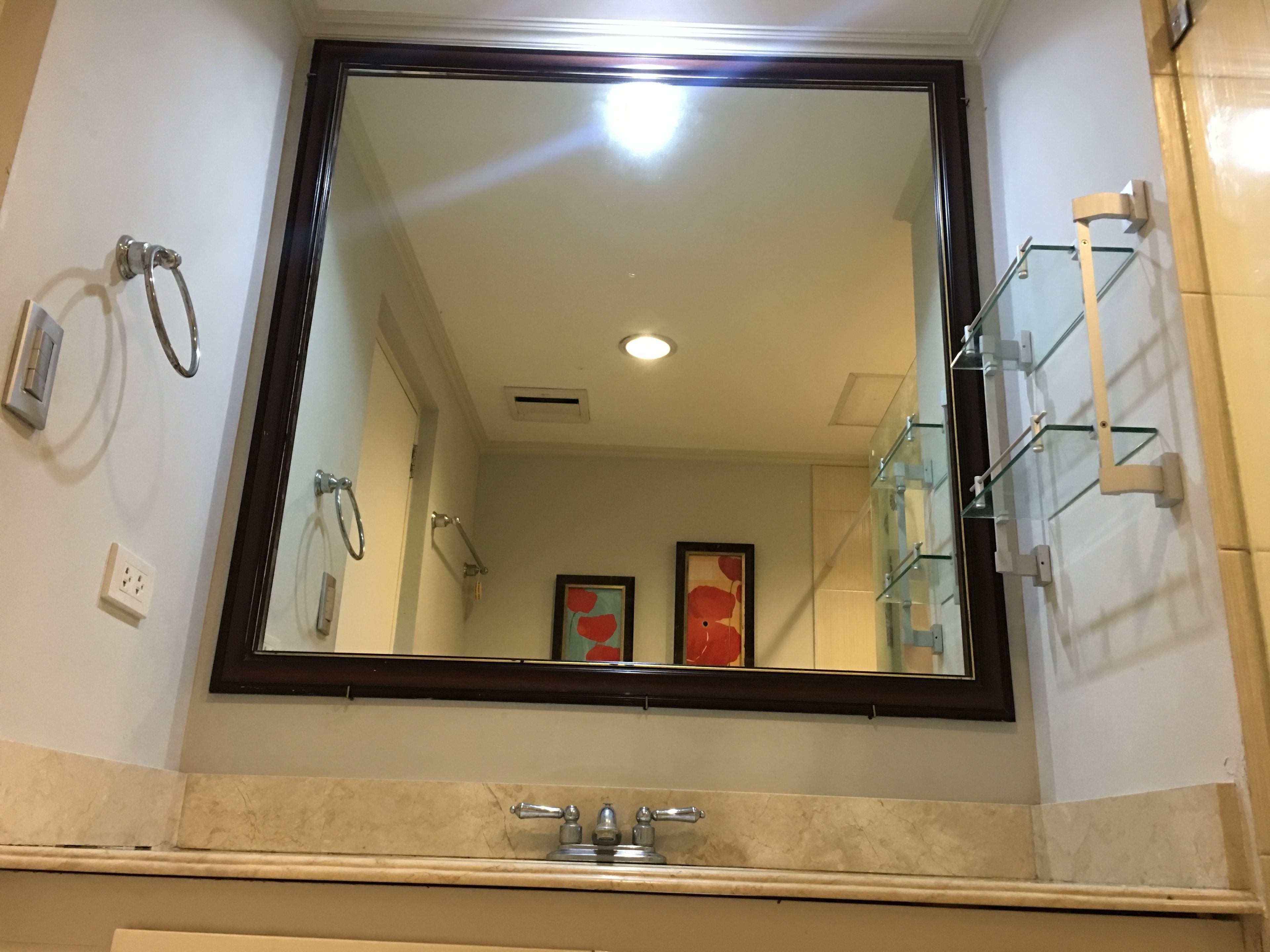 Un baño con un espejo grande, un lavamanos y una cabina de ducha de vidrio.