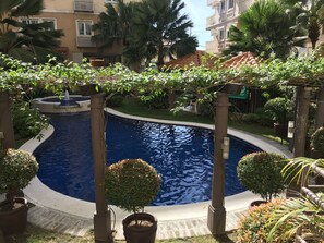 A swimming pool surrounded by potted plants and a pergola. - Jes & Warren's Place (Taguig)