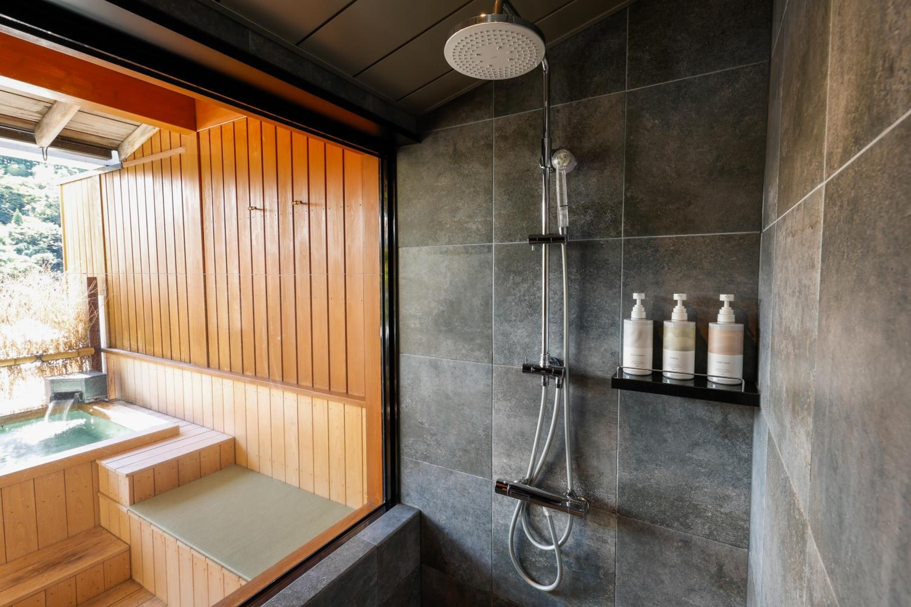Un baño moderno con un banco de madera, una ducha con cabezal de lluvia y un estante con artículos de aseo.