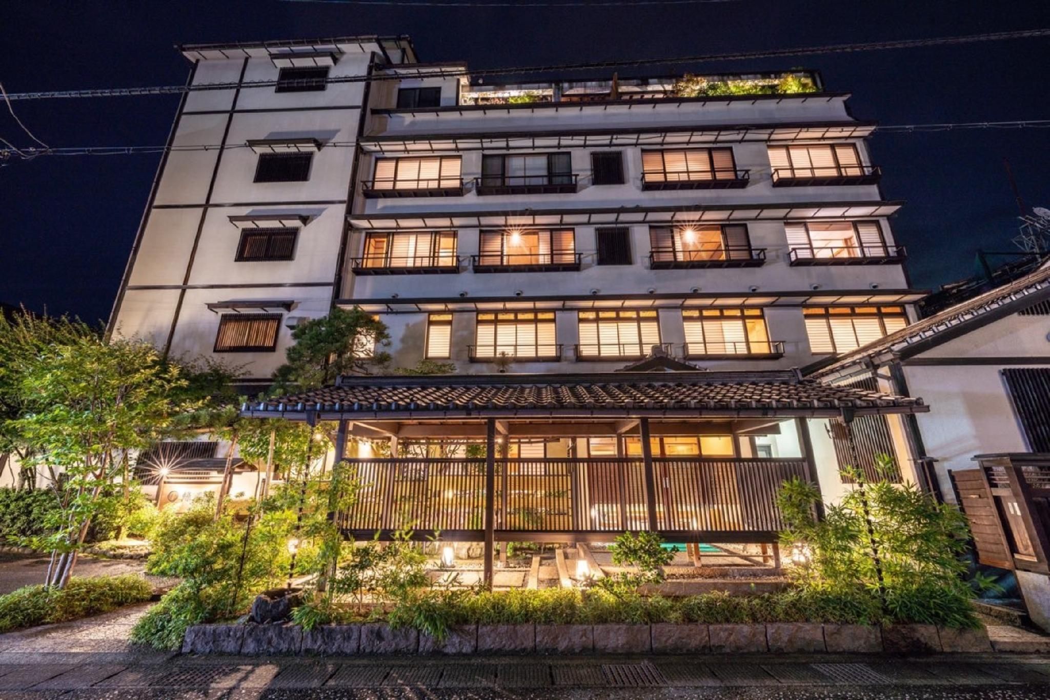 A multi-story building with a traditional Japanese architectural style, featuring a wooden veranda and a well-lit entrance.
