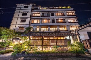 A multi-story building with a traditional Japanese architectural style, featuring a wooden veranda and a well-lit entrance. - Ryokufukaku (Toyooka)
