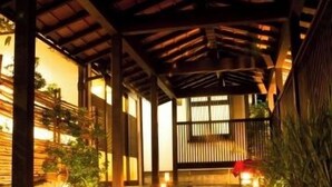 Een traditioneel Japans gebouw met een houten gevel, een overdekte ingang en een pad van stenen dat naar de deur leidt.