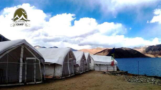 A row of tents with a flag, set against a backdrop of mountains and a lake. - TIH The Norling Camp - Pangong (Leh)
