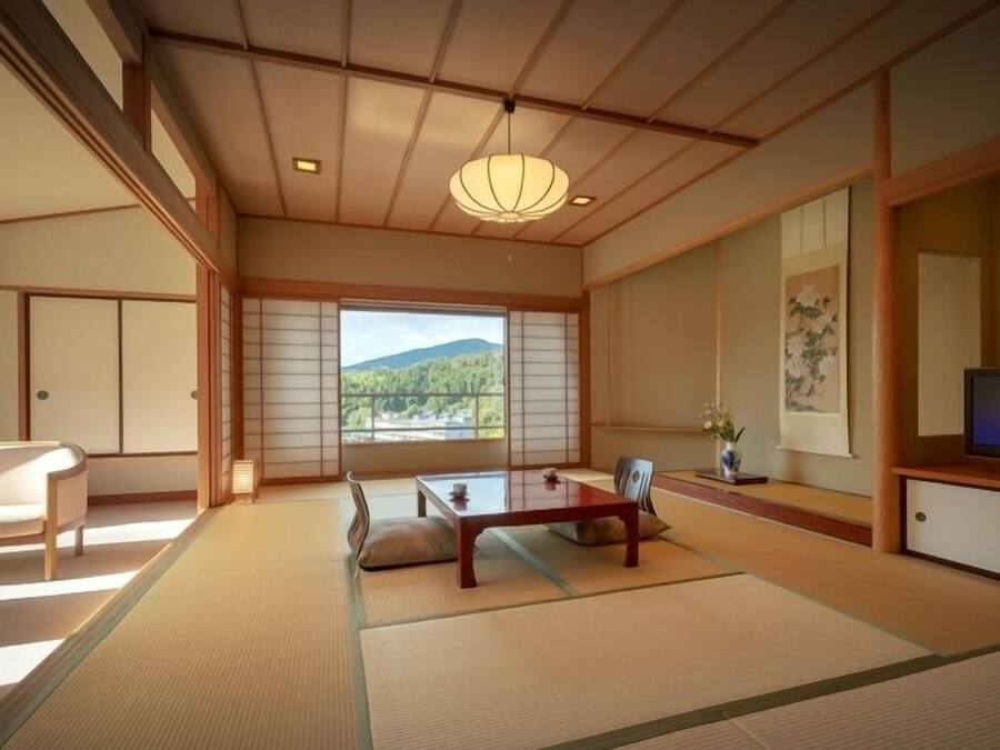 Une pièce de style japonais traditionnel, avec un sol recouvert de tatamis, une table basse, un canapé et un téléviseur.