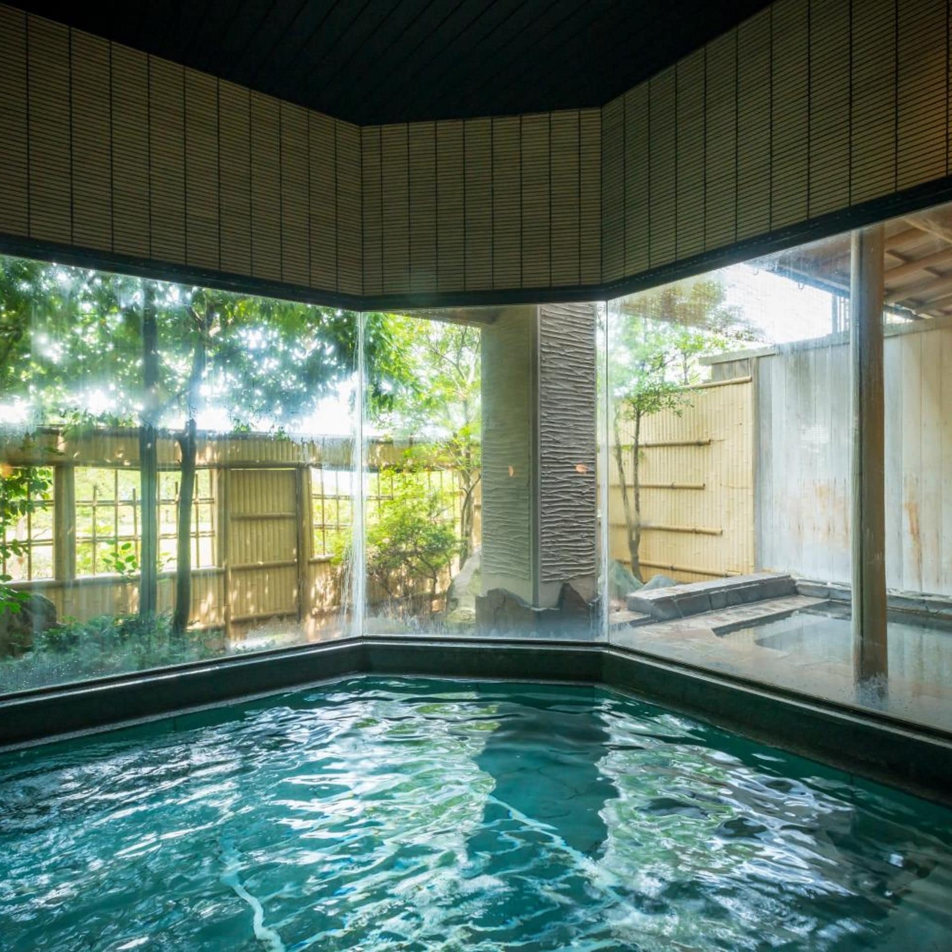 A hot tub with a view of a garden and a wooden fence.