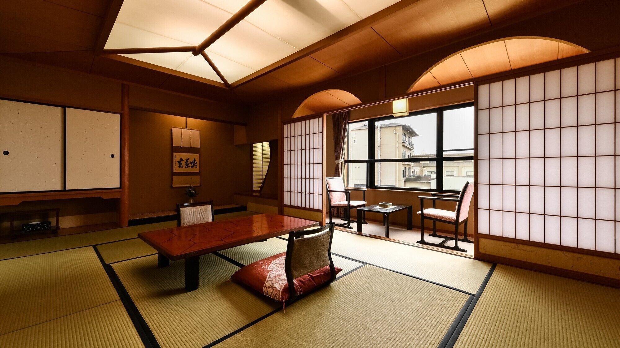 A traditional Japanese room with tatami flooring, a low table, chairs, and shoji screens.
