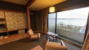 A room with a large window, a table, two chairs, a lamp, and a wooden cabinet. - Katayamazu Hot Spring Motoyu Hotel Kanoya Korakuen (Kaga)