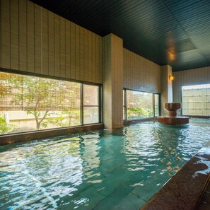 An indoor swimming pool with clear water, large windows, and a stone fountain. - Katayamazu Hot Spring Motoyu Hotel Kanoya Korakuen (Kaga)