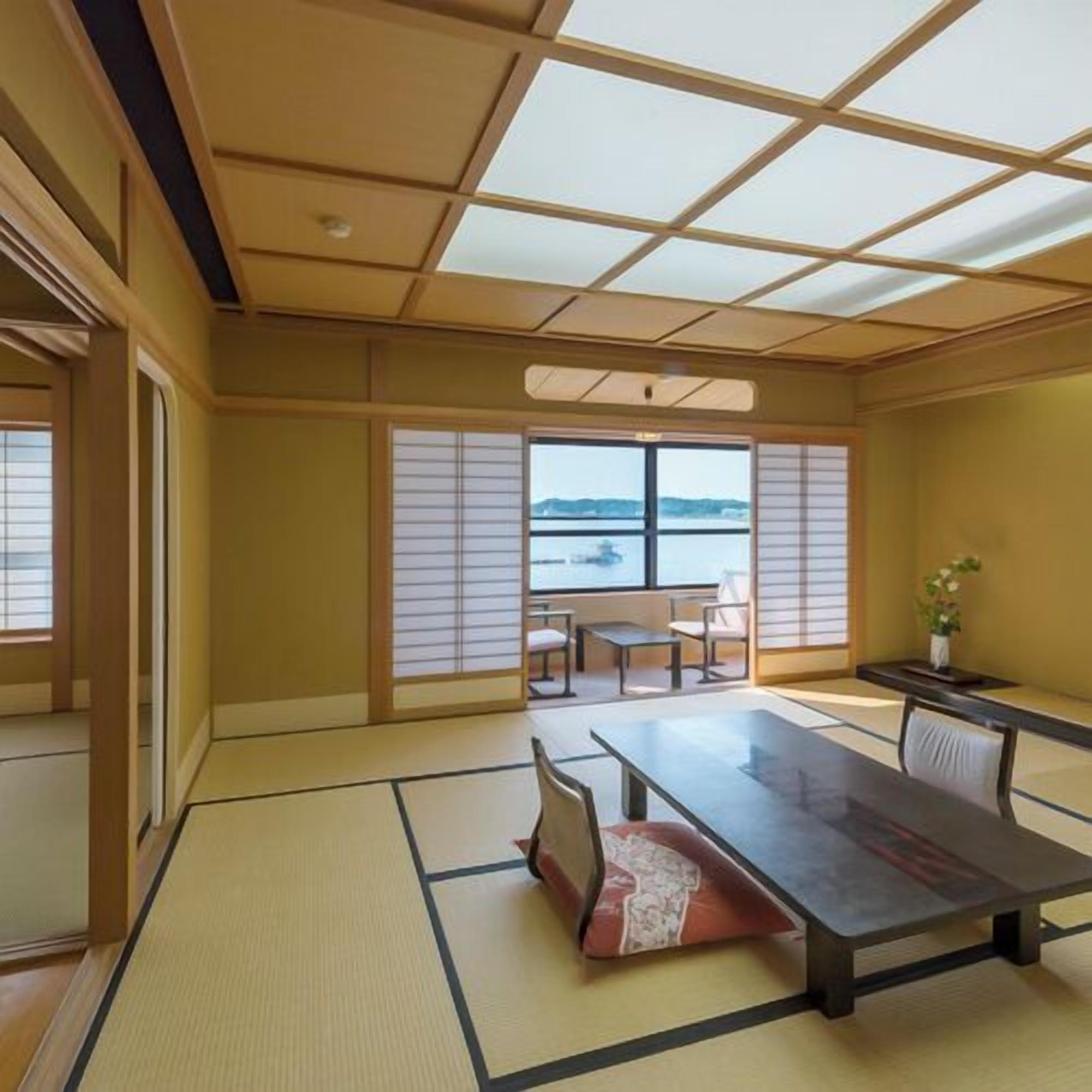Una habitación con tatami y vistas al mar, una mesa baja y puertas correderas tradicionales.