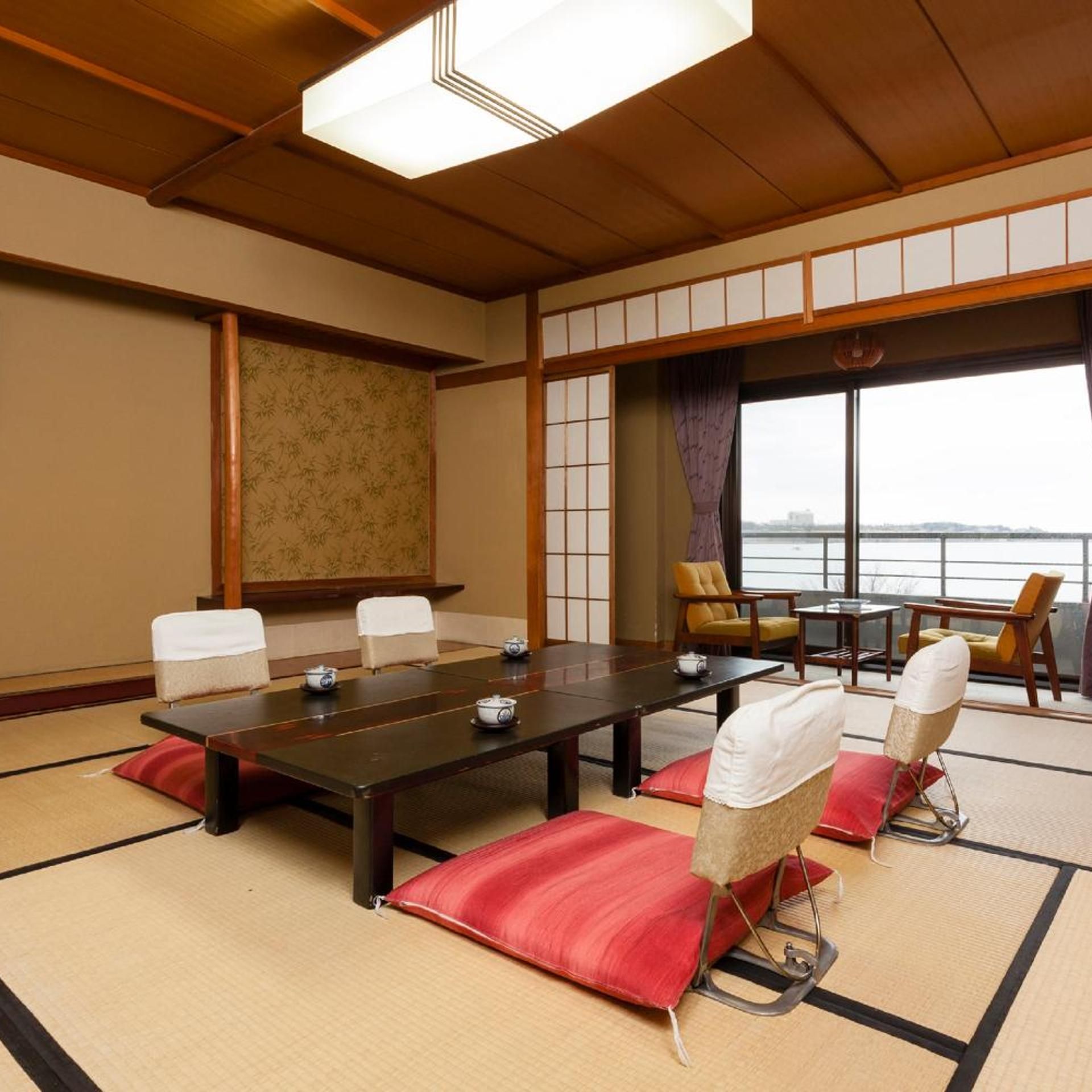A traditional Japanese-style meeting room with tatami flooring, a long table, and chairs.