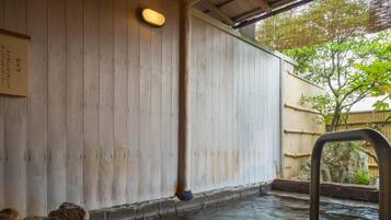 A traditional Japanese onsen with wooden walls and a stone bath area.