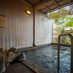 A traditional Japanese onsen with wooden walls and a stone bath area.