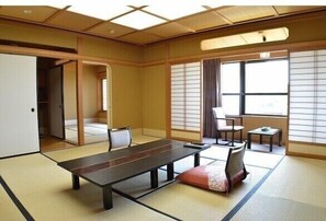A traditional Japanese room with tatami flooring, a low table, a chair, and sliding doors.