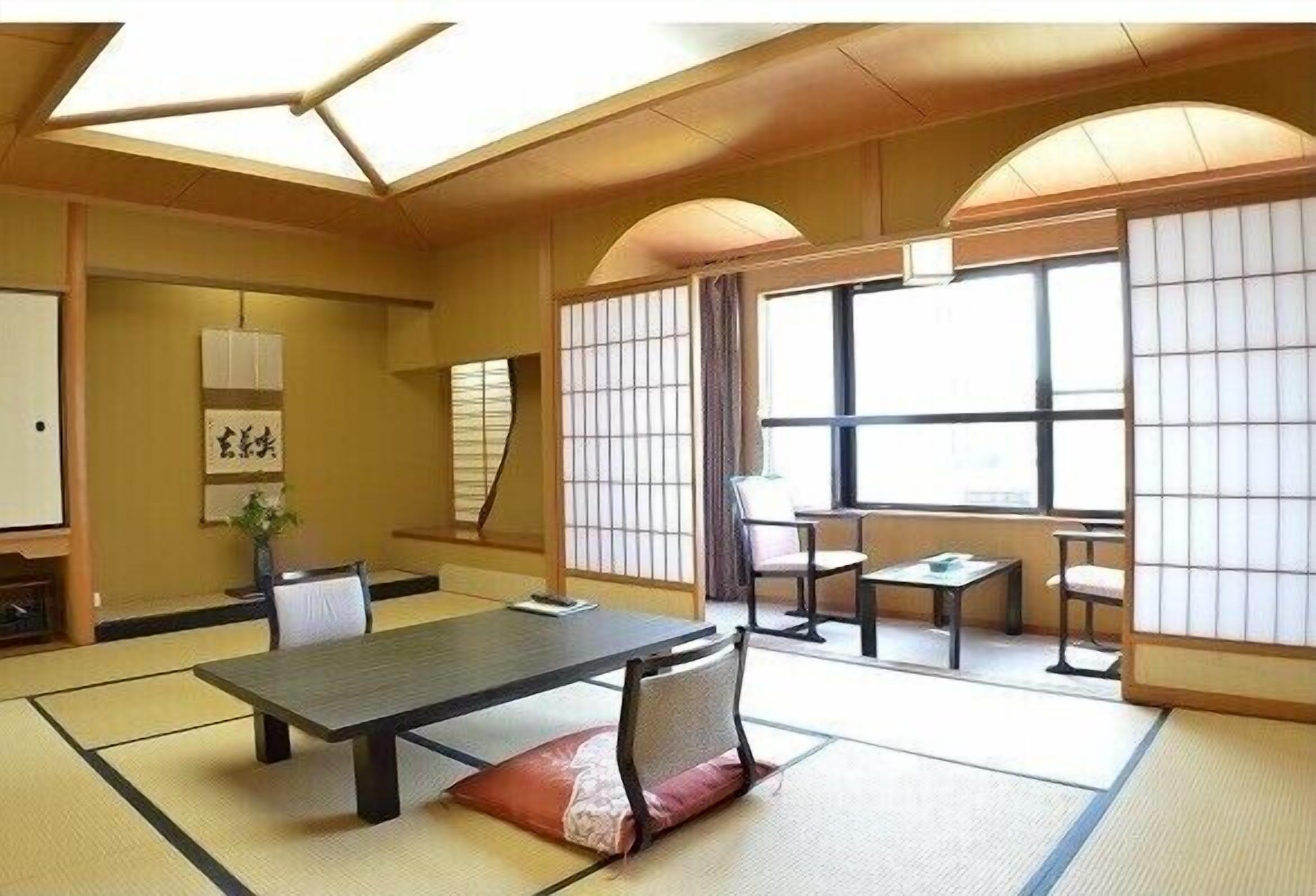 Una habitación japonesa tradicional con suelo de tatami, una mesa baja y puertas correderas.