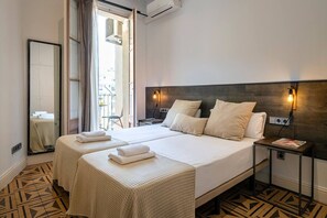 Une chambre d’hôtel avec un lit double, deux tables de chevet, un miroir et une vue sur la ville par la fenêtre.