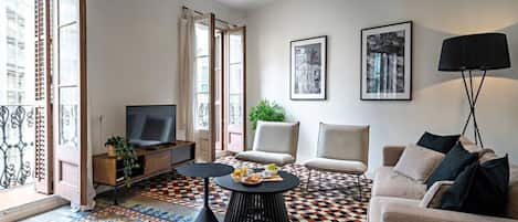 A modern living room with a television, seating, a coffee table, and artwork on the walls.