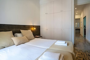 A hotel room with a large bed, a nightstand, a wardrobe, and a bathroom visible through an open door.
