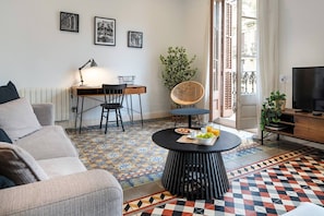 A living room with a sofa, a dining table with chairs, a TV, and a patterned floor. - Barcelona Balconies 31 - Habitat Apartments (Barcelona)