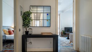 Un couloir avec une console noire, un miroir et une plante en pot.
