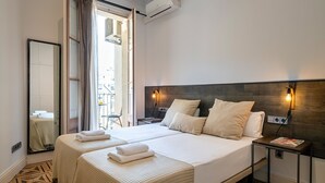 Une chambre d’hôtel avec un grand lit, deux tables de chevet, un miroir et une vue sur la ville par la fenêtre.
