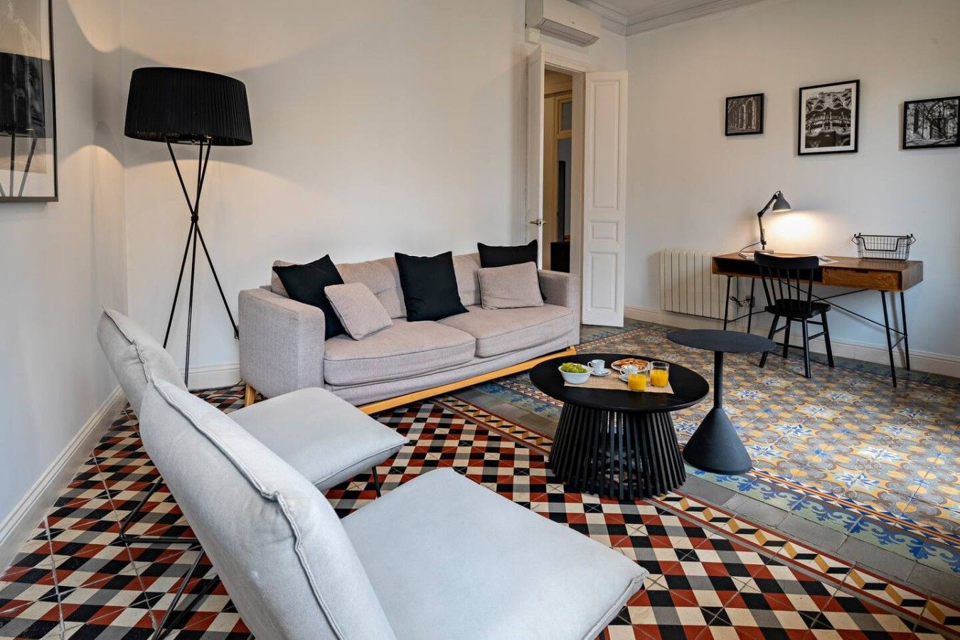 A living room with a sofa, armchairs, a coffee table, a floor lamp, and a dining area with a table and chairs.