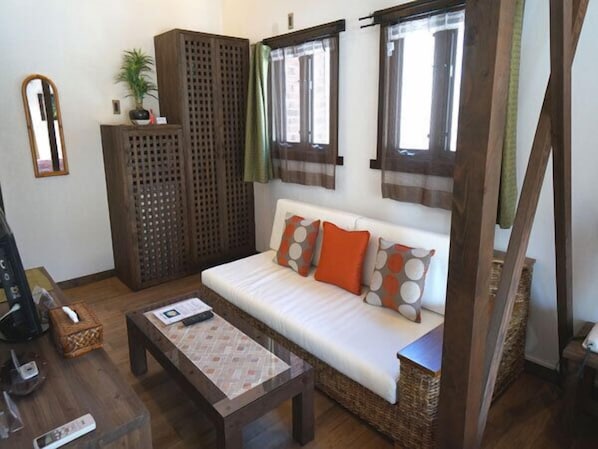 A cozy living room with a sofa, a coffee table, a mirror, and a wooden cabinet. - Estivant Club (Tsumagoi)
