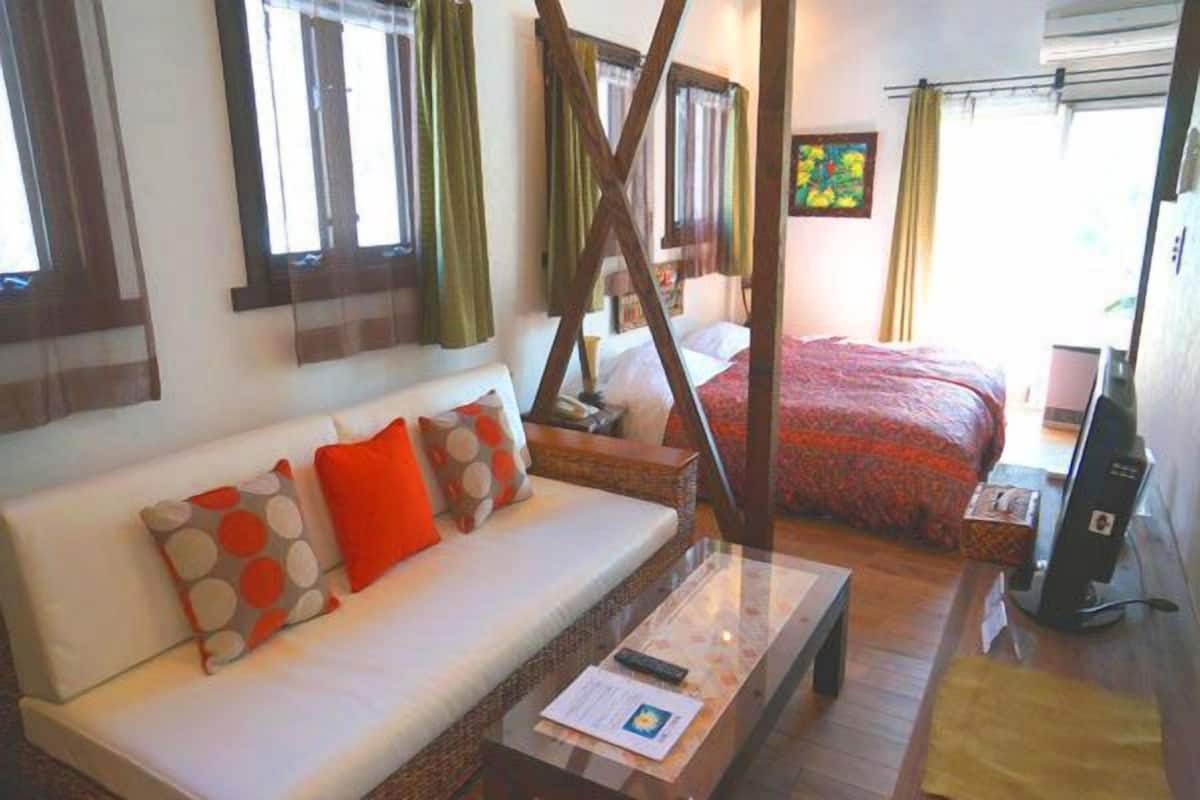 A cozy room with a sofa, a bed, a wooden coffee table, and a TV.