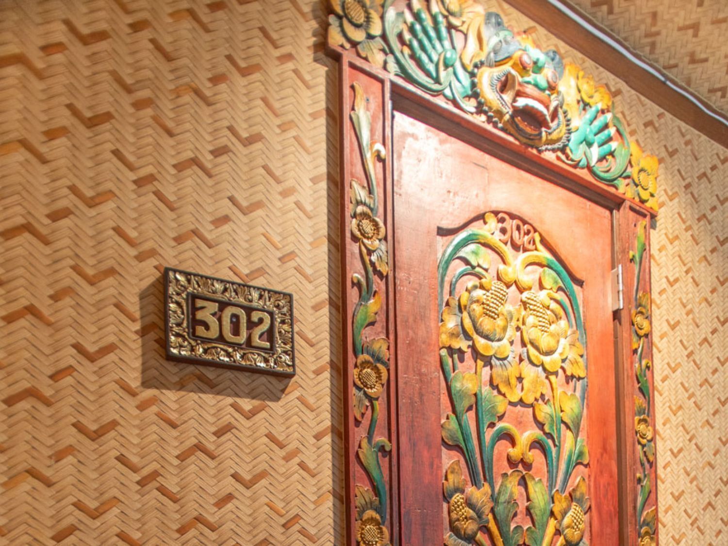 Uma porta de madeira com detalhes entalhados e uma placa numérica.