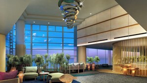 A spacious lobby with a high ceiling, large windows, and a modern chandelier.