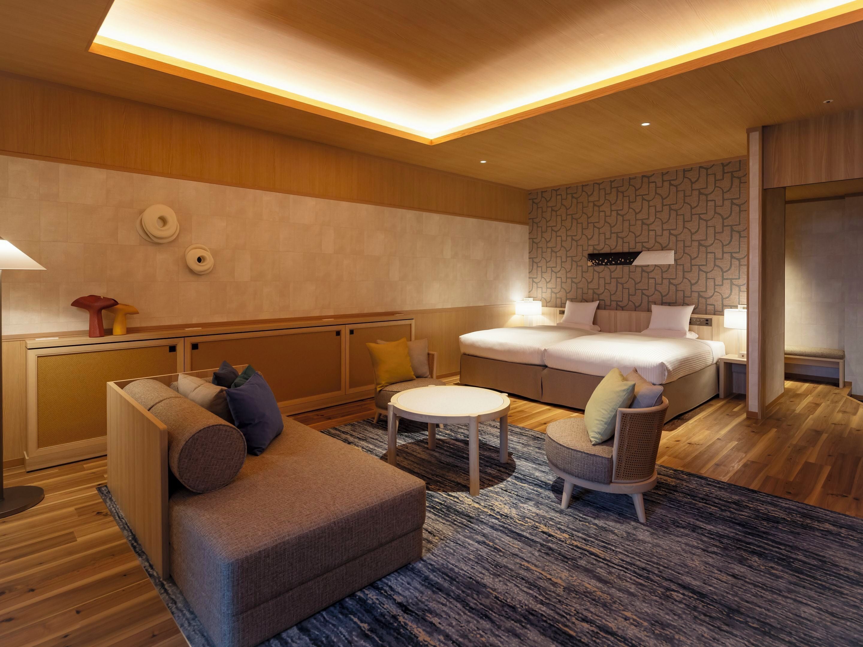 Et moderne hotelværelse med en stor seng, en sofa, et lille rundt bord og en stol.