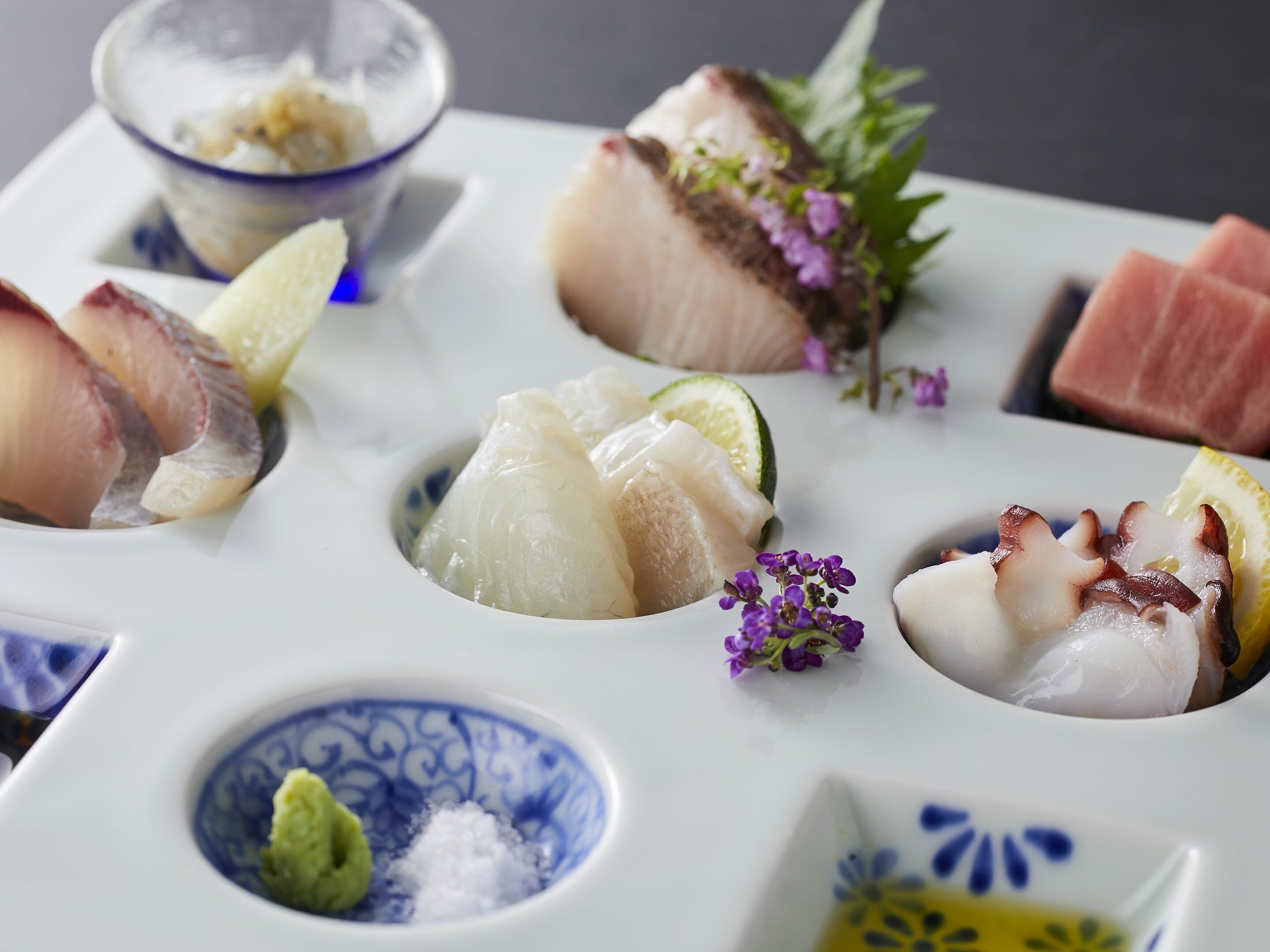 A variety of seafood dishes arranged on a white plate with a blue pattern.