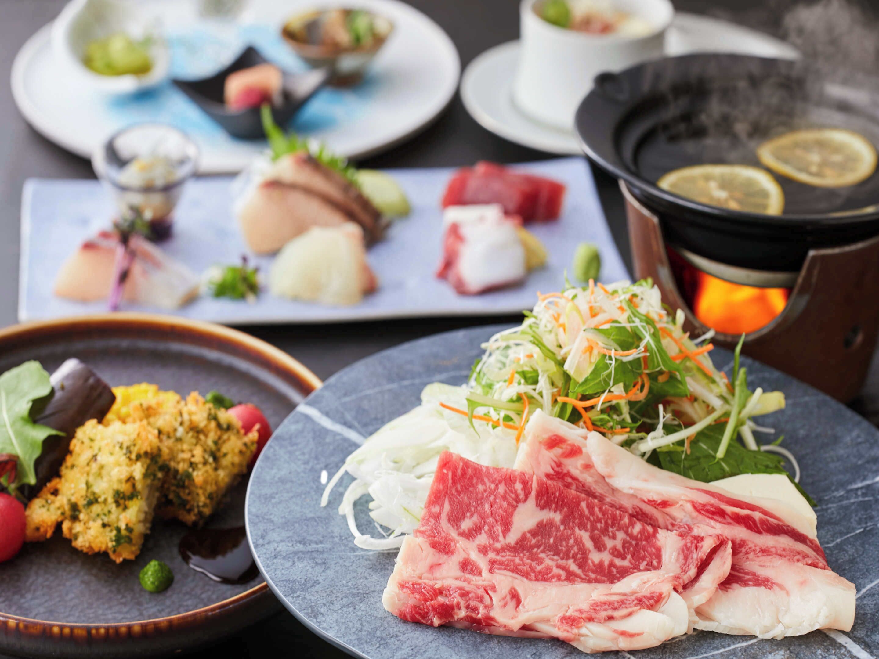 A variety of dishes on plates, including a salad, sliced meat, and other food items.