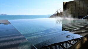 An infinity pool with clear water, a view of the sea, and a modern building structure.