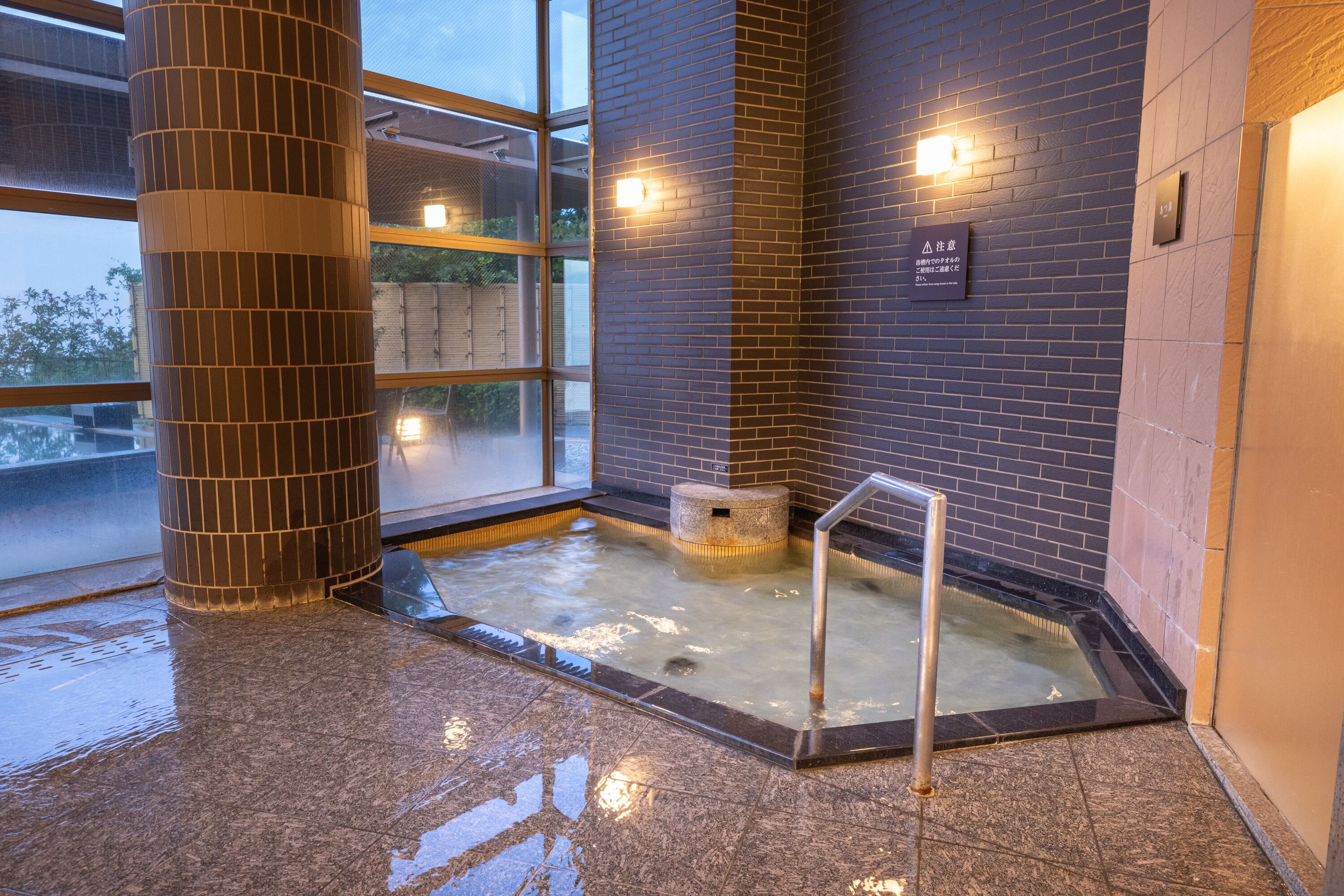 A spa area with a hot tub, tiled walls, and a window.