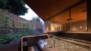 A modern spa area with a stone wall, bamboo plants, and a clear water feature.