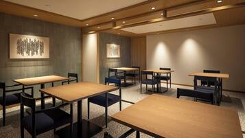A conference room with multiple tables and chairs, wooden ceiling panels, and recessed lighting.