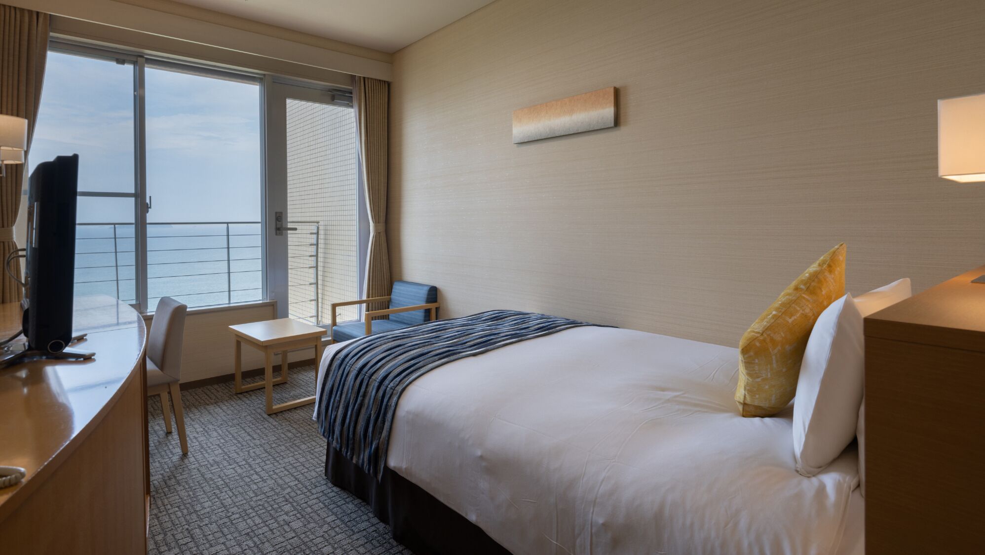 Habitación de hotel con cama, escritorio, silla, televisión y ventana con vistas.