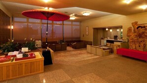 A hotel lobby with a reception desk, seating area, and large windows.