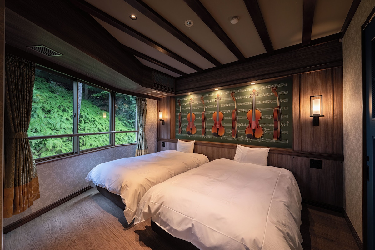 A room with two beds, large windows, a wall with musical instruments, and a green wall with a musical notes pattern.