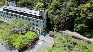 A multi-story building with a flat roof, surrounded by dense greenery. - Sanage Onsen Hotel Kinsenkaku (Toyota)