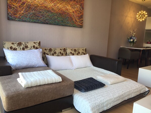 Ett modernt hotellrum med en stor säng, en soffa och ett skrivbord.