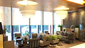 A modern lobby with seating areas, large windows, and decorative lighting.