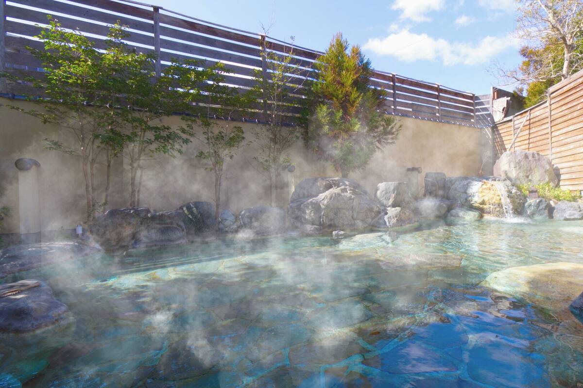 A hot spring area with clear water, rocks, and a wooden fence.